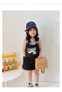 Close-up of retro black denim overall dress for girls with white Football 98 print