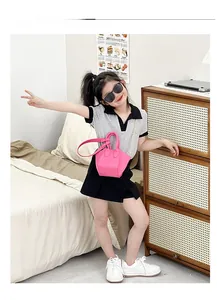 Detail showing a little girl wearing a bright pink mini tote bag with gold chain strap