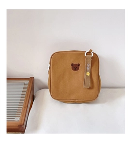 Détail de la broderie ours et de la sangle sur un sac à dos en toile marron