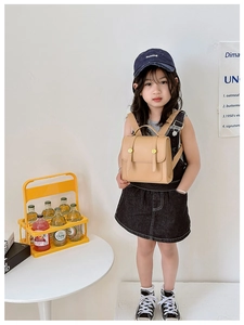 Detail view of khaki PU leather kids backpack with gold buckle on a child model