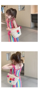 Detail of girls' woven straw bag featuring colorful floral embroidery and pink rope strap