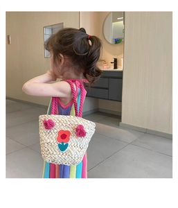 Girl's woven straw bag with floral embroidery and colorful strap worn by child model