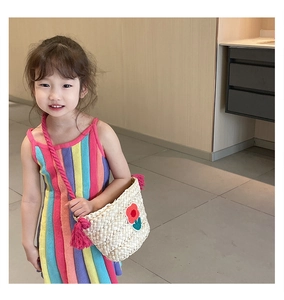 Detail of child wearing rainbow knit dress with a flower embroidered straw bag