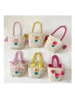 Detail view of woven straw handbags featuring colorful plush flower patches and rope handles
