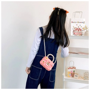 Détail du mini sac en gelée rose avec poignée en perles et motifs cartoon sur enfant
