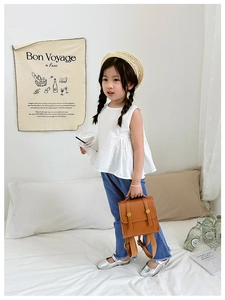 Close-up of a brown vintage leather toddler backpack paired with casual girl outfits