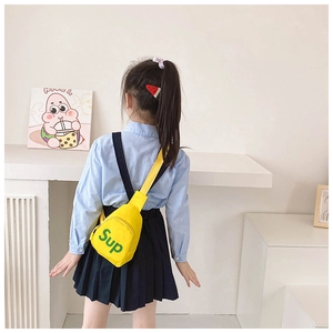 Detail view of a yellow canvas chest bag for kids with green letter print and adjustable strap