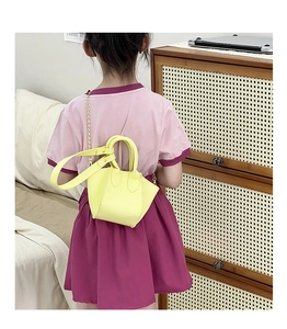 Detail showing the bright yellow mini wing bag worn by a child with a gold chain strap