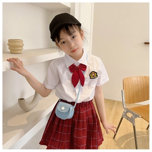 Detail of a girl school uniform set with white shirt, red bow, and plaid pleated skirt