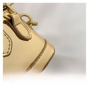 Macro shot of gold patent leather mini bag with fine stitching and metallic D-ring detail