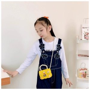 Gros plan d'un mini sac jaune en silicone avec anse en perles et charms floraux
