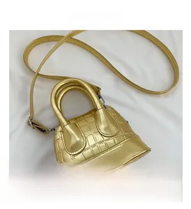 Detailed top view of gold crocodile embossed mini shell bag with adjustable strap