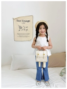 Detailed back view of a white PU leather mini backpack worn by a young girl
