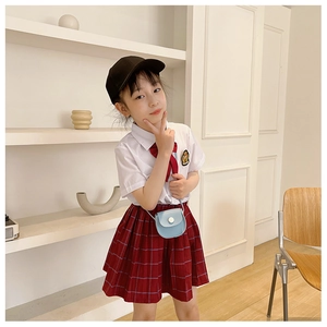 Detail of cute girls PU mini crossbody bag with button closure and red plaid pleated skirt