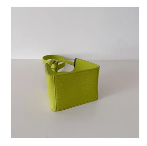 Detail of the trapezoidal neon green mini bag featuring a unique knotted shoulder strap