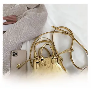 Detailed macro view of a mini golden patent leather bag compared to a smartphone