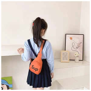 Detail of orange canvas chest bag for kids featuring a black Sup letter print and zipper
