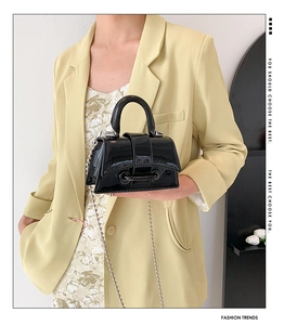 Fashionable black glossy patent leather mini handbag with silver chain strap on model