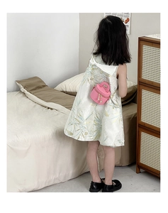 Détail d'un petit sac seau rose avec chaîne dorée et perles sur une robe verte