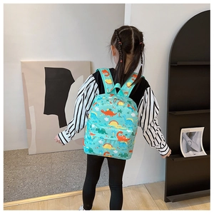 Detailed view of child wearing a teal backpack with colorful cartoon dinosaur patterns
