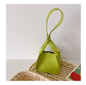 Detail of lime green mini PU leather bag with twisted handle in a woven basket