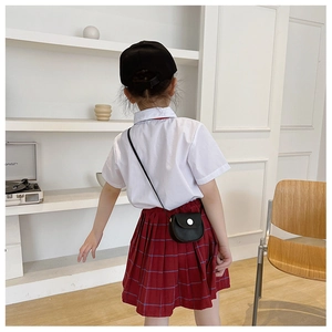 Rear view of a girl wearing a black mini crossbody bag with a red plaid school skirt