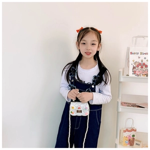 Détail du sac blanc matelassé pour fille avec breloques de dessin animé et chaîne en perles