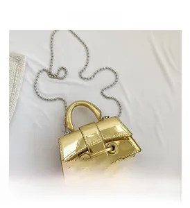Detail of a shiny gold mini handbag with metallic finish and beaded chain strap