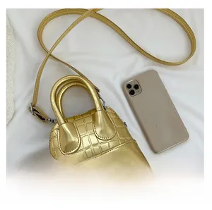Top view of gold crocodile embossed mini shell bag with smartphone for size reference