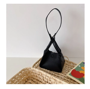 Detail of a black triangle pyramid bag with lychee texture and long shoulder strap