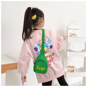 Close-up of child wearing a vibrant green canvas chest bag with yellow Sup letter print
