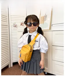 Detail of child wearing a bright yellow canvas chest bag with black fashion lettering