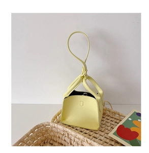 Detail of yellow lychee grain leather mini bag with circular handle in woven basket