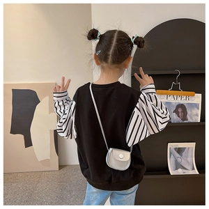 Detail of a girl wearing a black sweatshirt with striped sleeves and silver crossbody bag