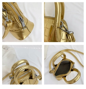 Detail view of gold crocodile embossed mini shell bag with dual handles and zip closure