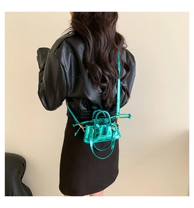 Detail of mini shiny green patent leather shell bag with adjustable shoulder strap and drawstring