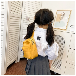Detail of yellow nylon kids crossbody bag featuring black fashion lettering and blue zipper