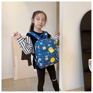 Blue kids space backpack with rocket print worn by a child in a minimalist room