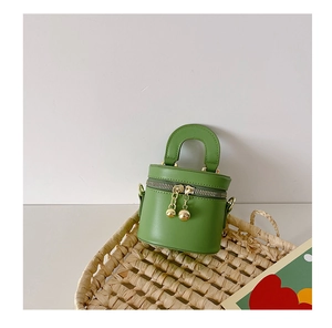 Détail d'un mini sac seau vert herbe pour filles avec des boules dorées au zip