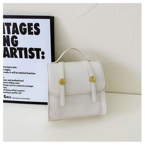 Close-up of retro cream white PU leather mini backpack with golden metal buckles