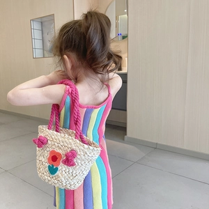 Girl wearing a handmade woven straw tote bag with pink tassels and a rainbow striped dress