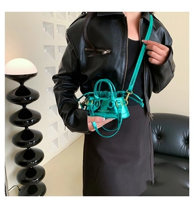 Detail of a shiny mint green mini shell bag with metallic finish and gold hardware