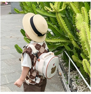 Détail d'un sac à dos enfant en toile crème avec broderie ours porté par un enfant