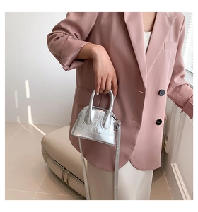 Detail of silver shell-shaped mini bag featuring crocodile embossed texture and metallic finish