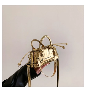 Detail of gold mirror patent leather mini shell bag with fashion typography print