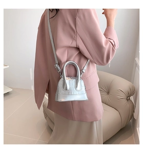 Silver mini shell bag with crocodile texture worn by a model in a pink blazer