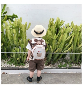 Détail d'un sac à dos blanc pour enfant en toile avec broderie d'ours sur un modèle