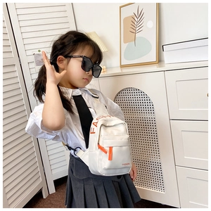 Close-up of kids white canvas chest bag with red FASHION letters and orange zipper details