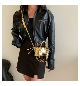 Close-up of golden metallic mini shell bag with mirror finish and fringe detail