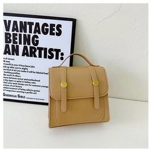 Detail view of vintage camel PU leather backpack with gold metal snaps and square structure
